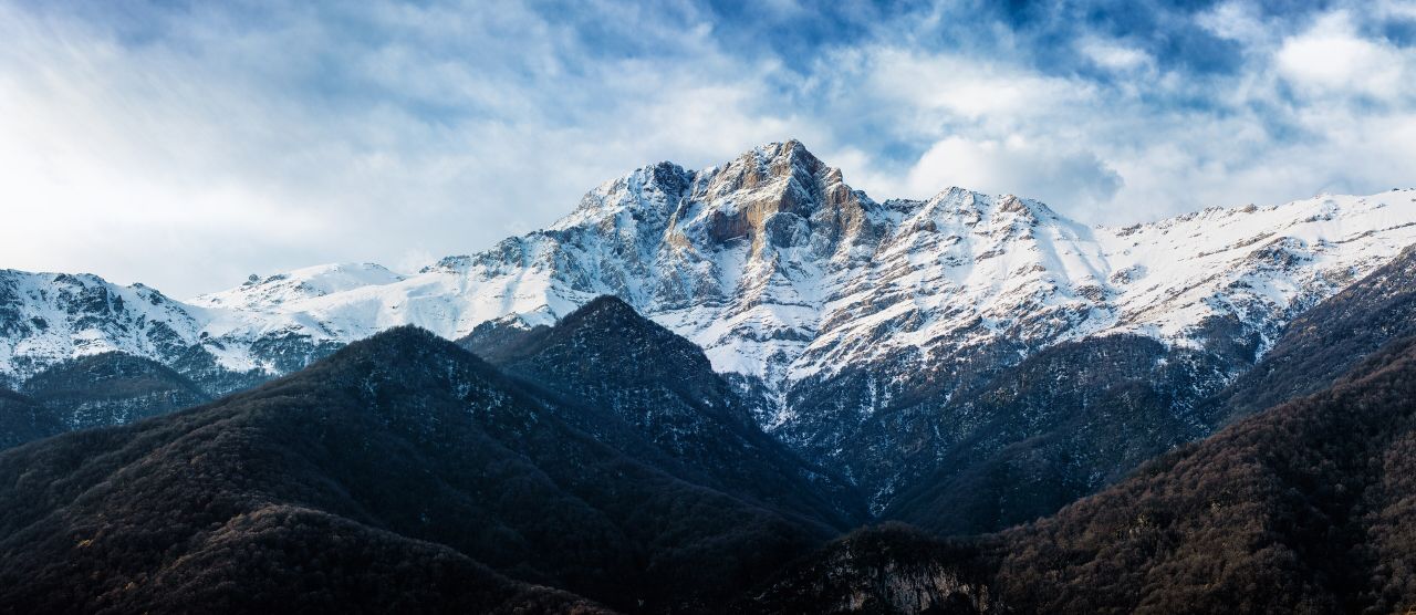 Mount Khustup under snow above dark forested ridges