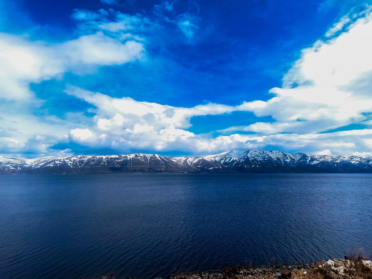 The deep blue water of Lake Sevan, snowy mountains across it